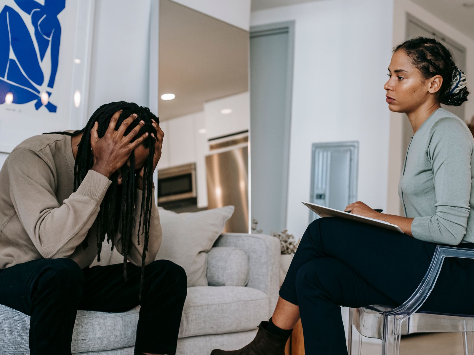 A man sitting with his head in his hands while a therapist listens