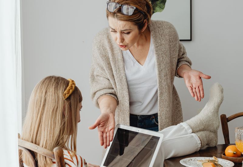 A parent gesturing in frustration during an argument with her teenage daughter
