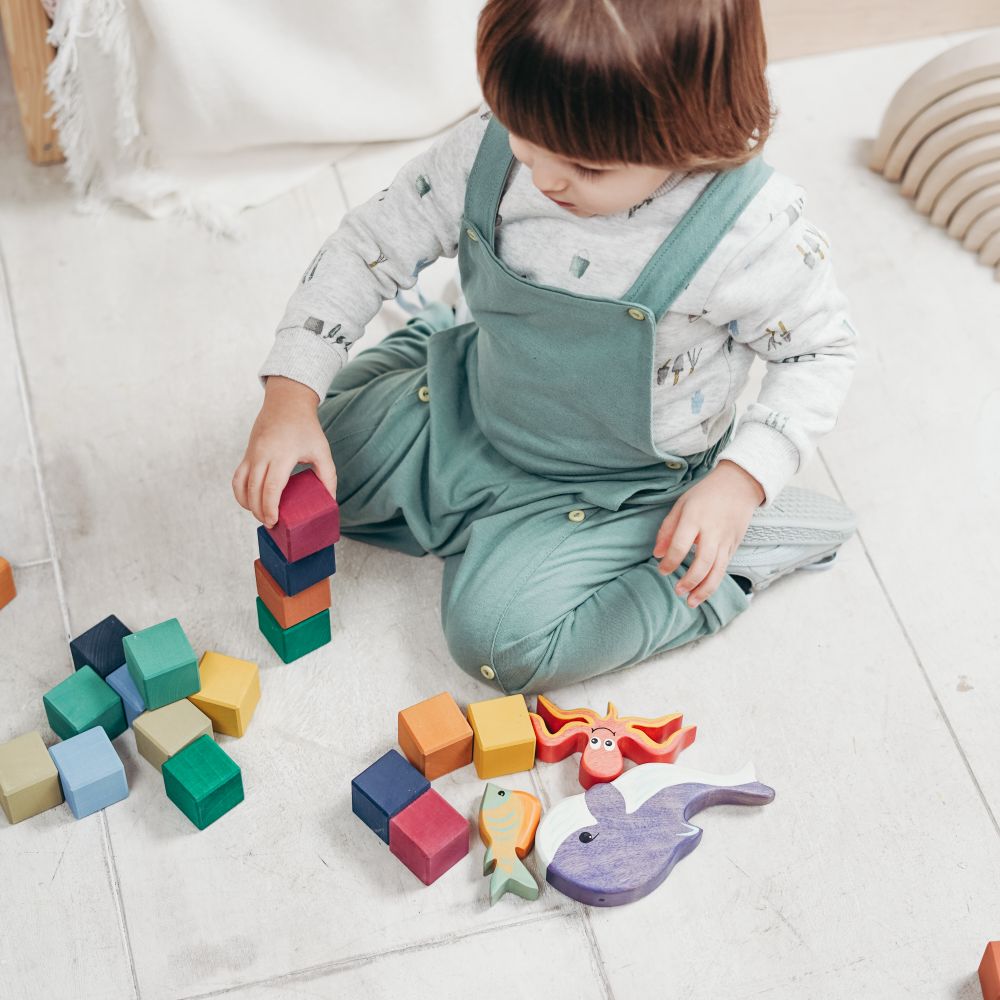 A child building with wooden blocks and toy figures