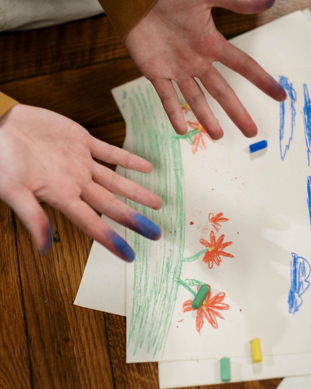 A child’s hands resting on a crayon drawing