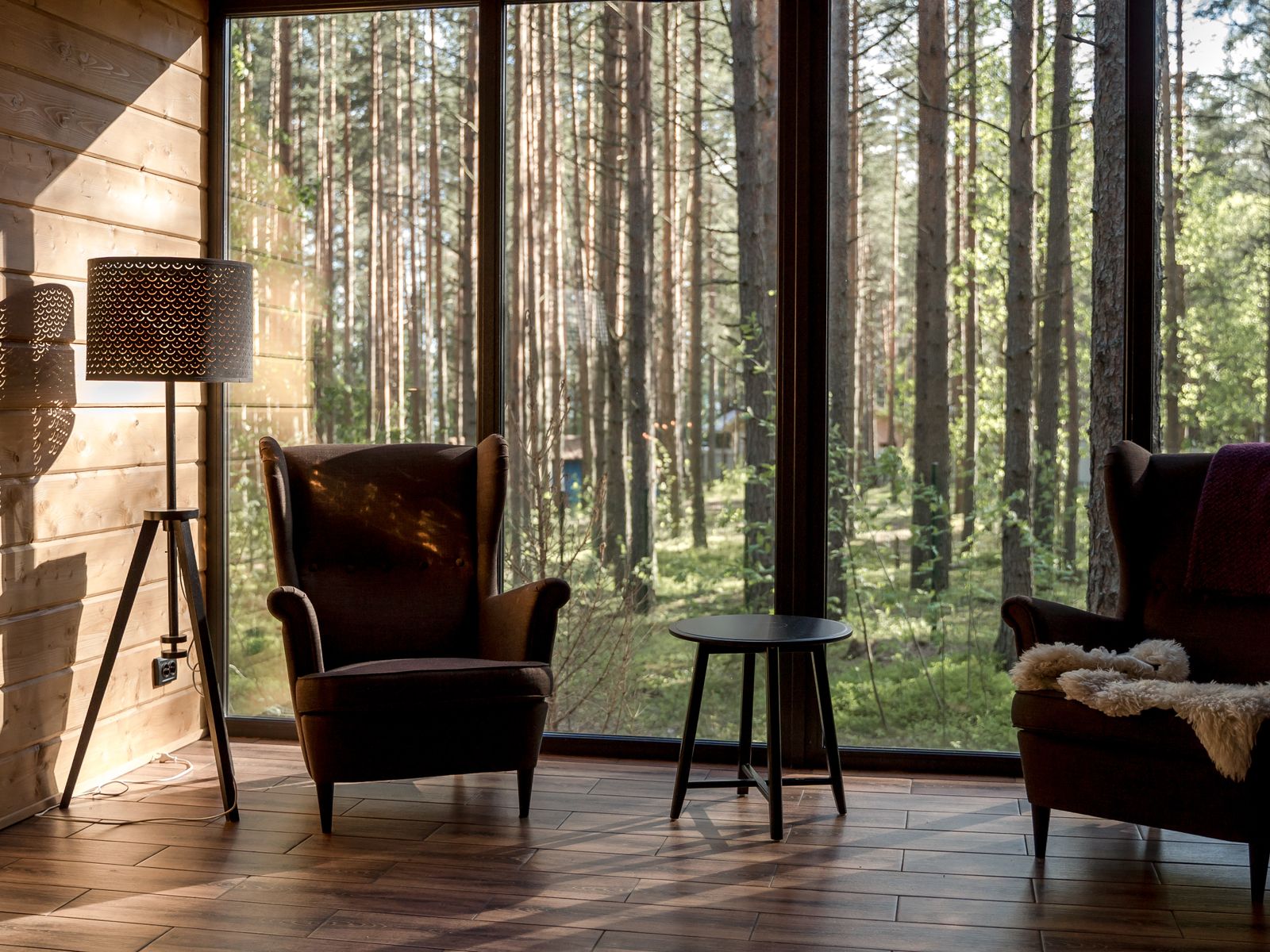 Two armchairs facing each other beside a window looking onto woodland